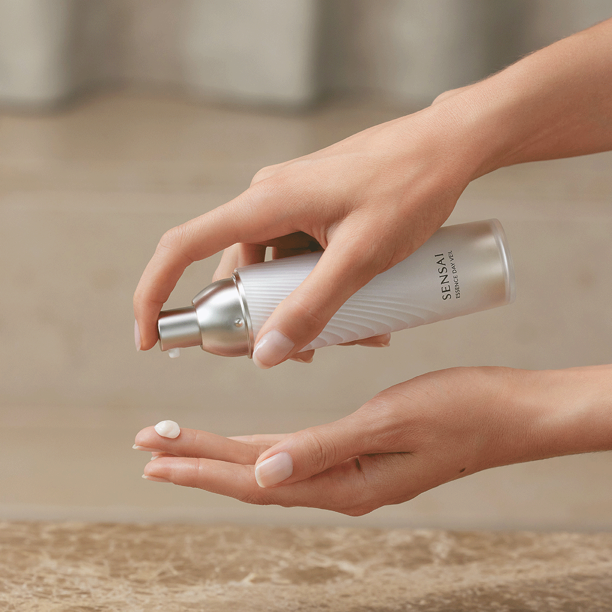 Essence Day Veil di SENSAI sul tavolo con 2 prodotti complementari Absolute Silk sullo sfondo, seguiti dalla texture del prodotto sulla mano 